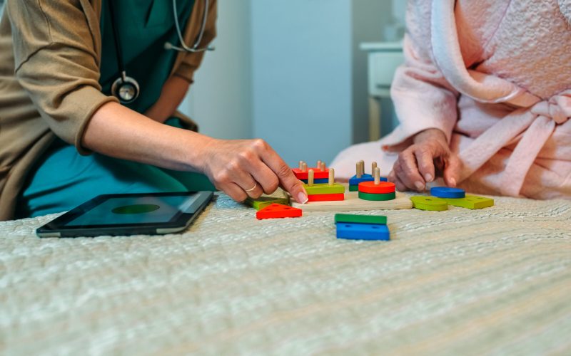 Female doctor showing geometric shape game to elderly female patient with dementia